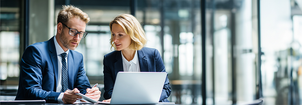 
        Businessmann und Businessfrau sitzen vor einem Notebook.
    