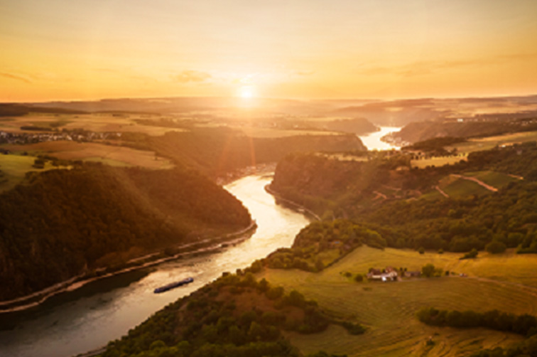(c) MINISTERIUM FÜR WIRTSCHAFT, VERKEHR, LANDWIRTSCHAFT UND WEINBAU RHEINLAND-PFALZ. Blick von oben über einen Fluss mit Landschaft und einem Flussschiff bei Sonnenuntergang