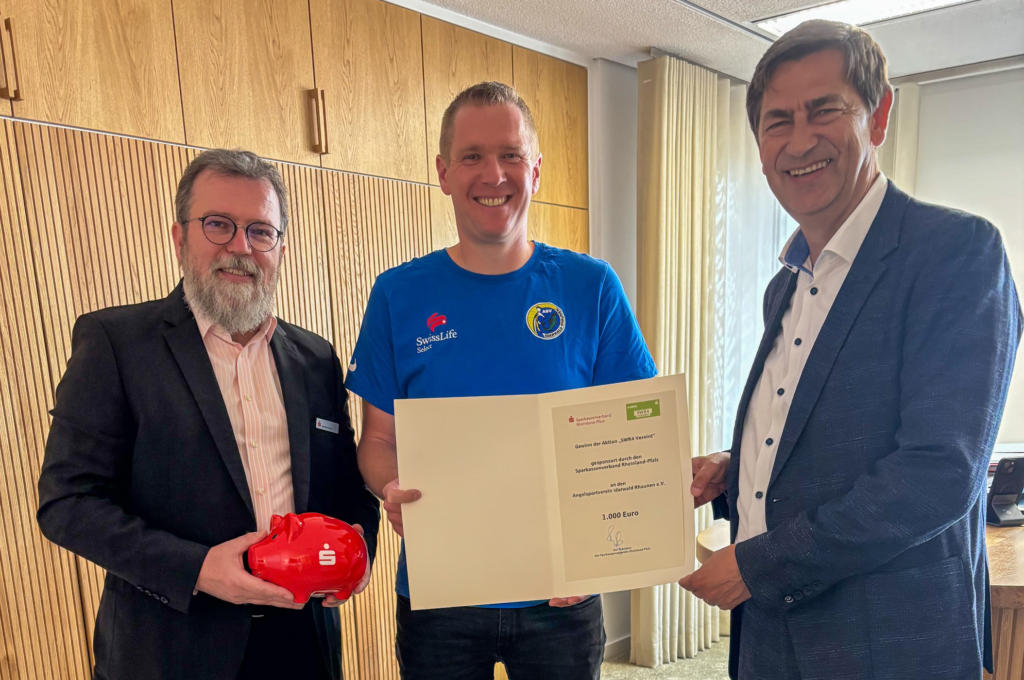Gruppenfoto mit drei Männern, SVRP-Geschäftsführer Herr Roman Frank bei der Preisübergabe Gewinnspiel SWR4-vereint an den Sportverein Rhaunen in Idar-Oberstein