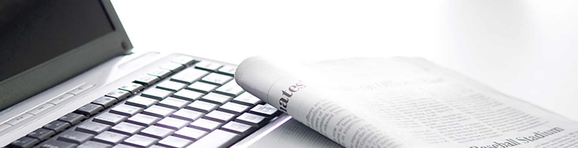 Aufgeklappter Laptop und Tageszeitung