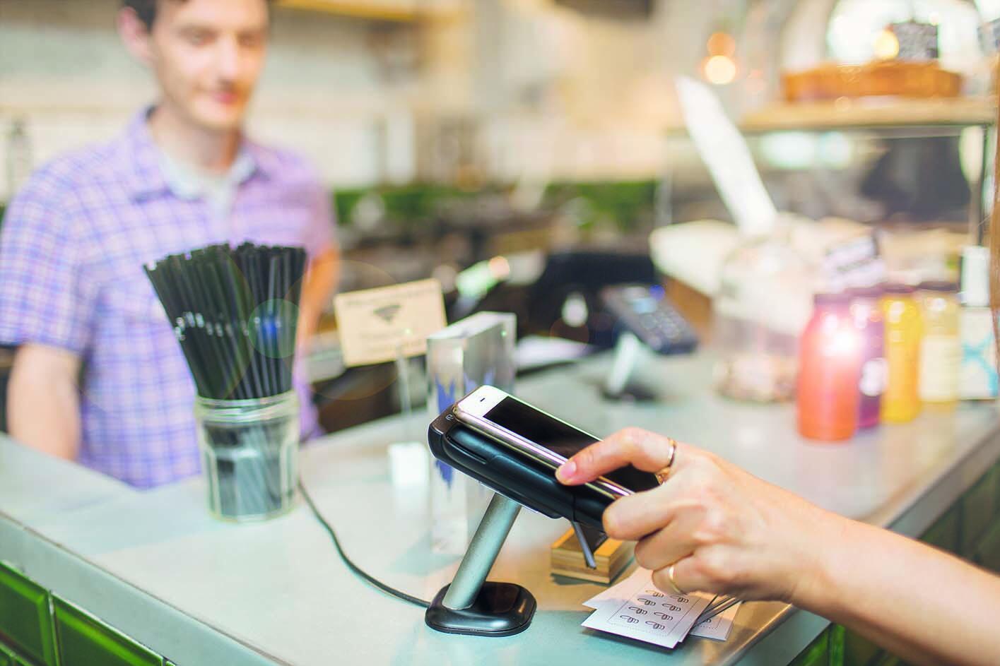 ein Frau bezahlt in einem Café mit einem Smartphone