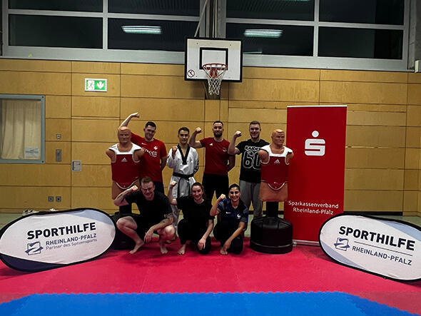 Gruppe mit jungen Sportlern und Sportlerinnen posieren in einer Turnhalle für ein Gruppenfoto.