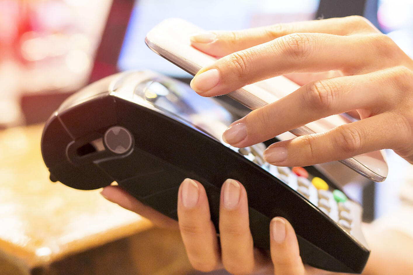 eine Person hält ein Smartphone an eine Lesegerät
